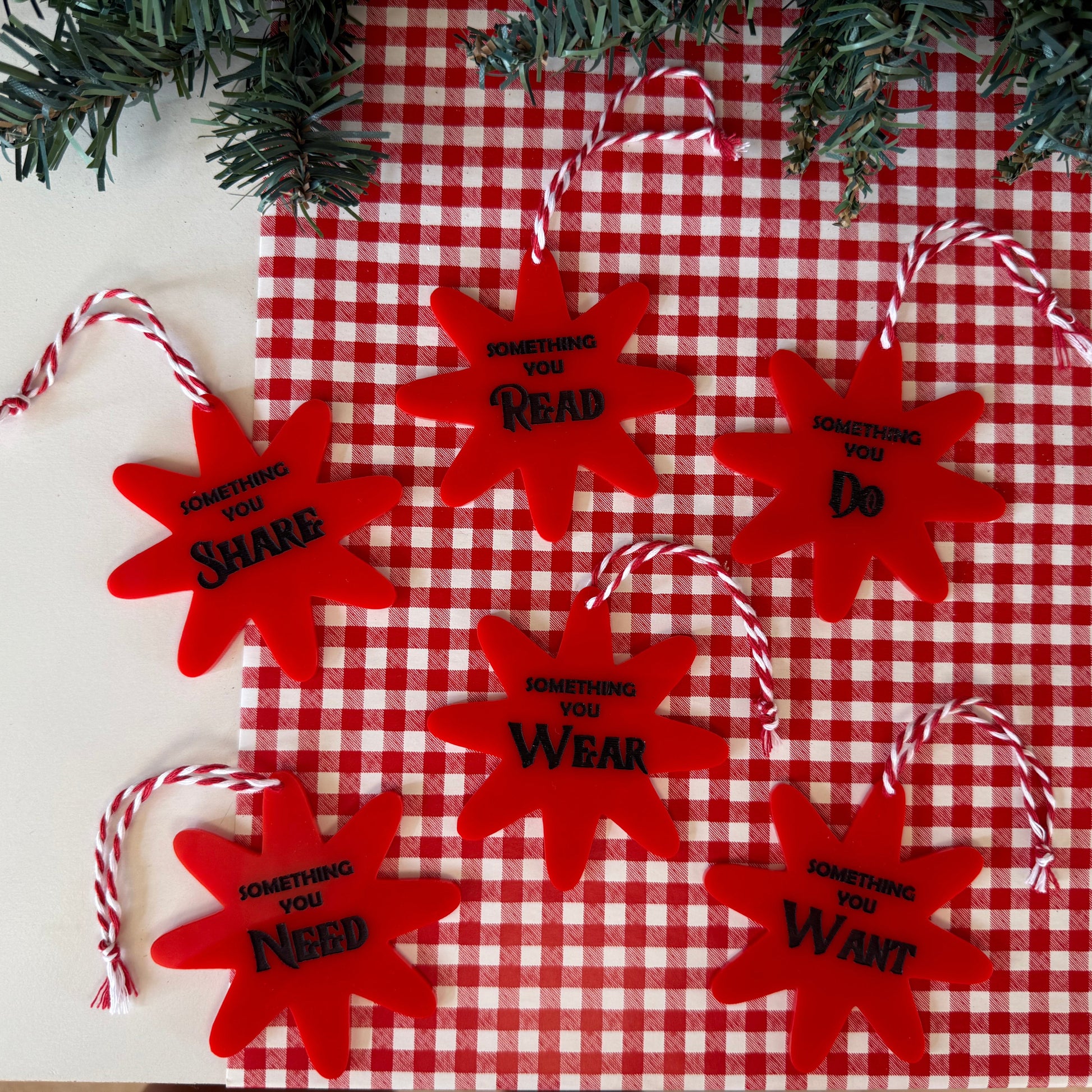 Red star-shaped ornaments with text on a red and white checkered tablecloth.
