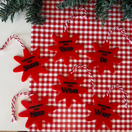 Red star-shaped ornaments with text on a red and white checkered tablecloth.